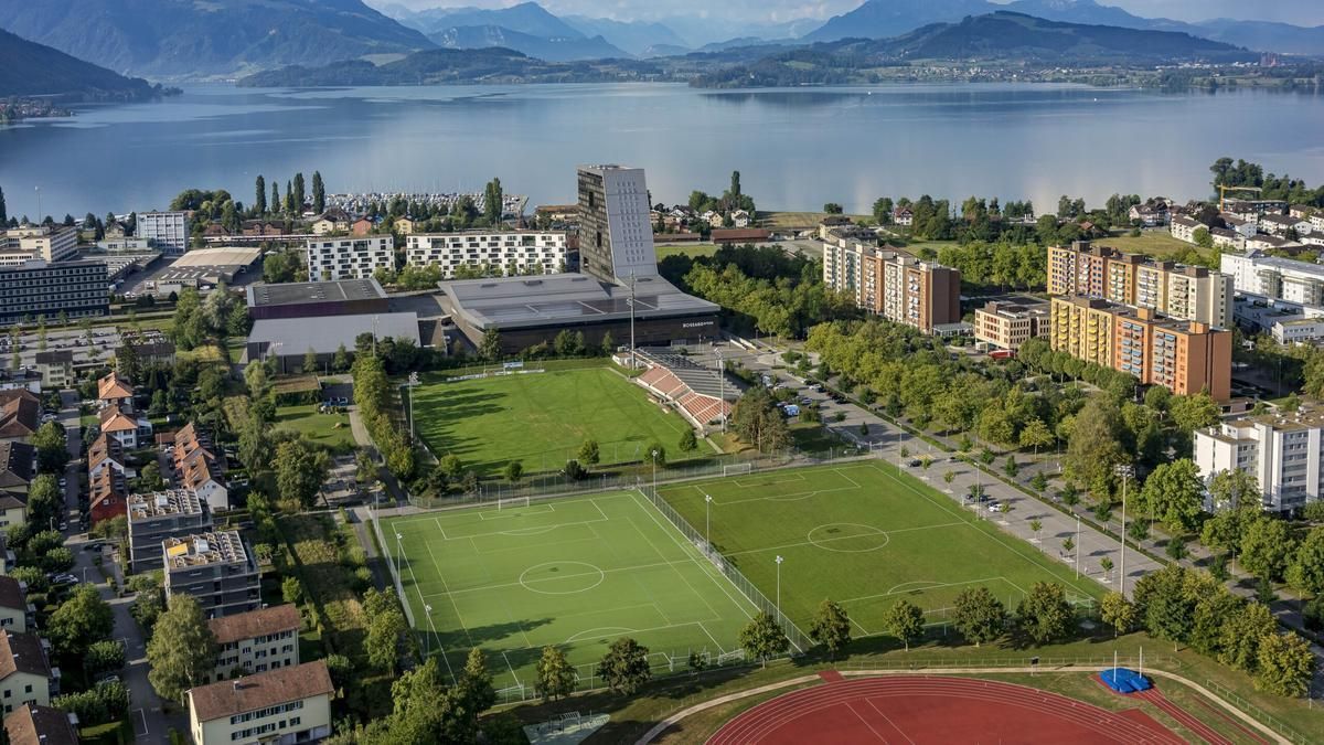 Bild zeigt die Schrägansicht des bestehenden Sportareals der Bossardarena mit dem Zugersee im Hintergrund.