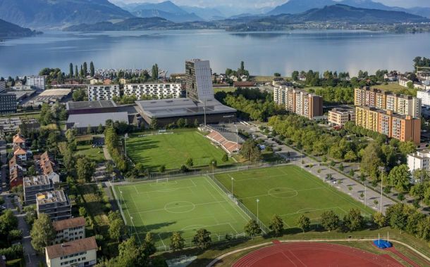 Bild zeigt die Schrägansicht des bestehenden Sportareals der Bossardarena mit dem Zugersee im Hintergrund.